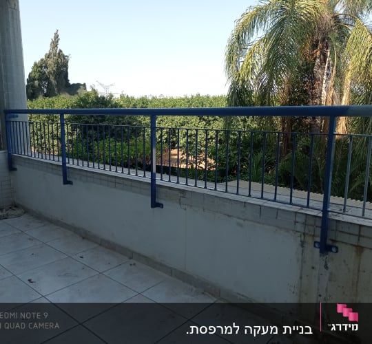 מעקה מתכת כחול על מרפסת מרוצפת